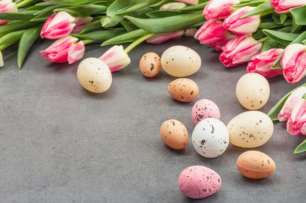 Páscoa plana leiga com ovos coloridos e tulipas Decoração tradicional cartão festivo feriado conceito pedra cinza fundo de concreto espaço de cópia