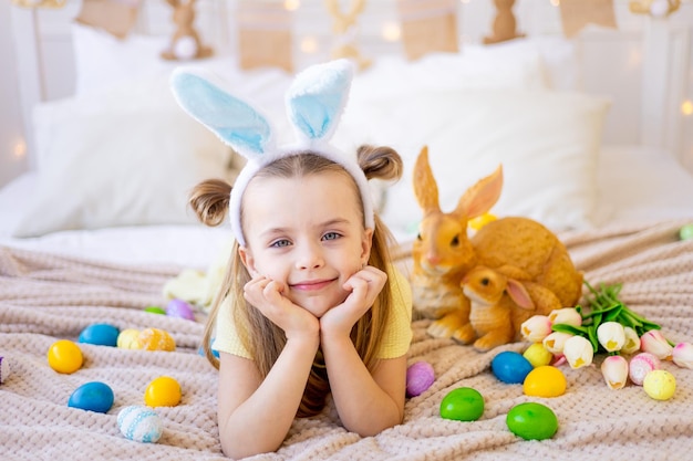 Páscoa uma garotinha entre ovos coloridos pintados em orelhas de coelho está se preparando para o feriado sorrindo e se divertindo