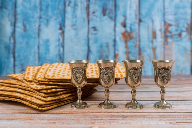 Pascua cuatro vasos de vino y pan de fiesta judío matzá sobre tabla de madera.