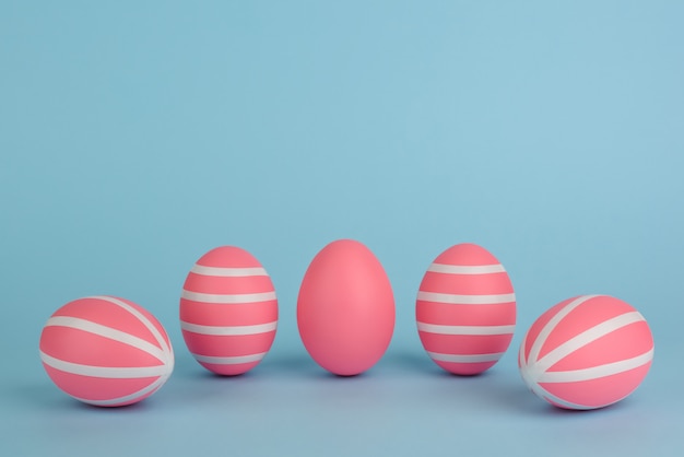 Pascua decorado huevos de color rosa. Cinco rayas de color rosa huevos en una fila sobre un fondo azul. Rayas blancas en huevos pintados de rosa. Copia espacio Feliz tarjeta de pascua. Colorido concepto de Pascua.