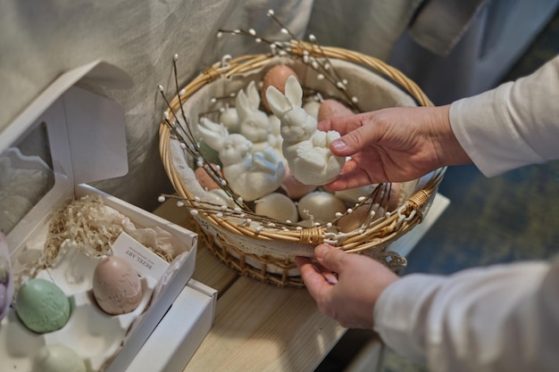 La Pascua deleita a la mujer que sostiene una canasta de conejitos y velas en forma de huevo