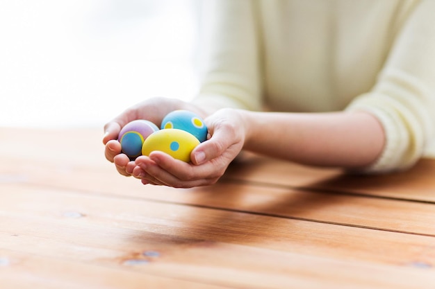 Pascua, días de fiesta, tradición y concepto de la gente - cerca de las manos de la mujer que sostienen los huevos de Pascua coloreados