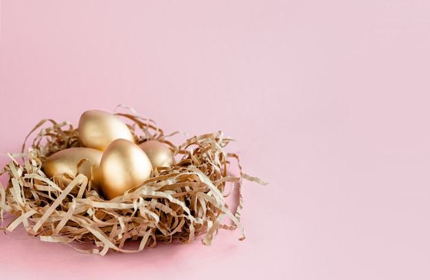 Pascua oro decorado huevos en el nido sobre fondo blanco. Espacio mínimo de la copia del concepto de pascua para el texto. Vista horizontal superior, flatlay.