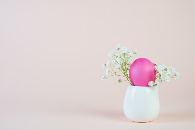 Pascua pintó el huevo rosado en un soporte sobre un fondo beige pastel.