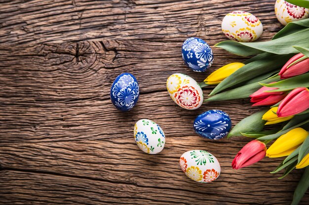 Pascua de Resurrección. Huevos de Pascua hechos a mano y tulipanes de primavera en la mesa de madera vieja.