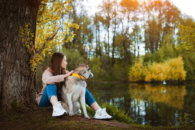 Paseadora de perros con una mascota caminando en la naturaleza junto al río