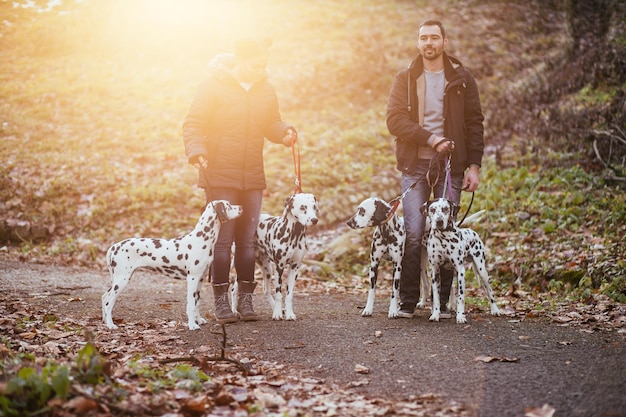 Paseadores de perros con perros dálmatas disfrutando en el parque.