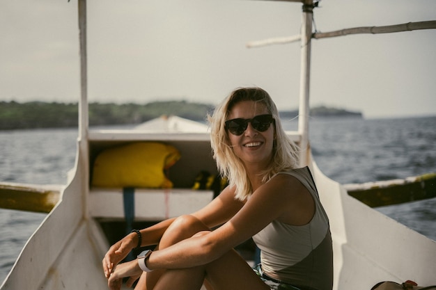 Paseo en barco en Bali. Una joven con gafas de sol navega en un barco hacia una isla cercana.