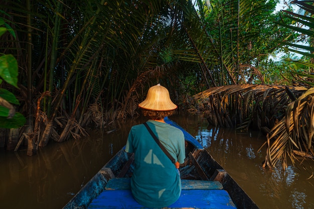 Paseo en barco en la región del Delta del río Mekong, Ben Tre, Vietnam del Sur. Turista con sombrero vietnamita en crucero en los canales de agua