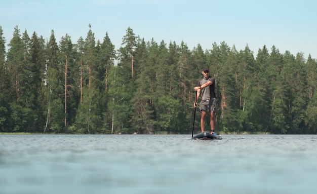 Paseo en barco en una tabla de remo en un pintoresco lago del bosque