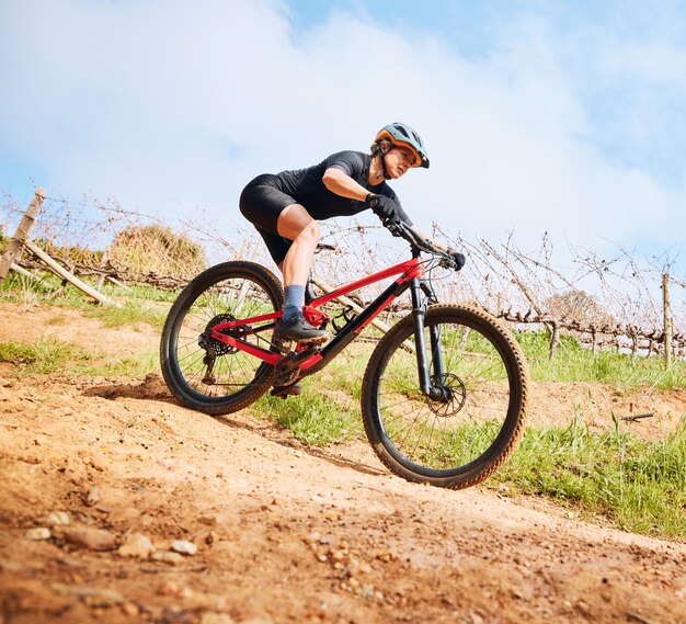 Paseo en bicicleta por la colina y mujer al aire libre en una bicicleta con velocidad para carreras deportivas en un camino de grava Ejercicio físico y atleta rápido haciendo entrenamiento deportivo en la naturaleza en un sendero del parque para cardio y entrenamiento