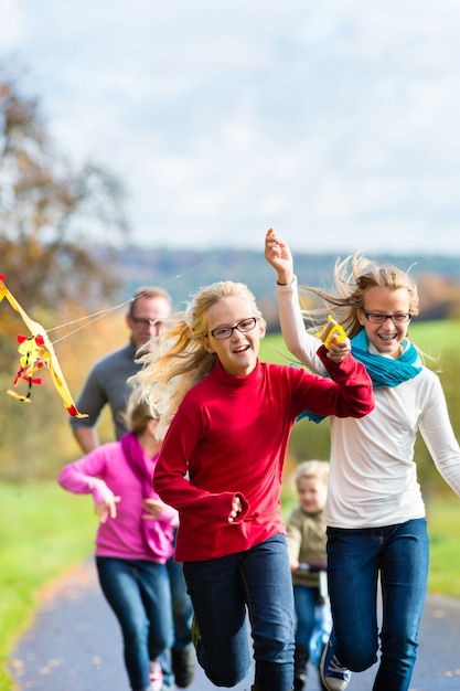 Paseo de la familia en el bosque de otoño volar cometa