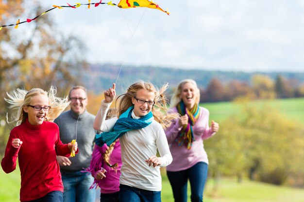 Paseo de la familia en el bosque de otoño volar cometa