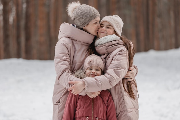 Paseo familiar de invierno en el bosque Madre e hija se divierten en invierno en el bosque en un clima soleado y helado El abrazo de una madre