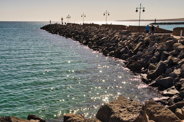 Foto paseo con hermosas farolas formadas por una línea de rocas en puerto del rosario fuerteventura