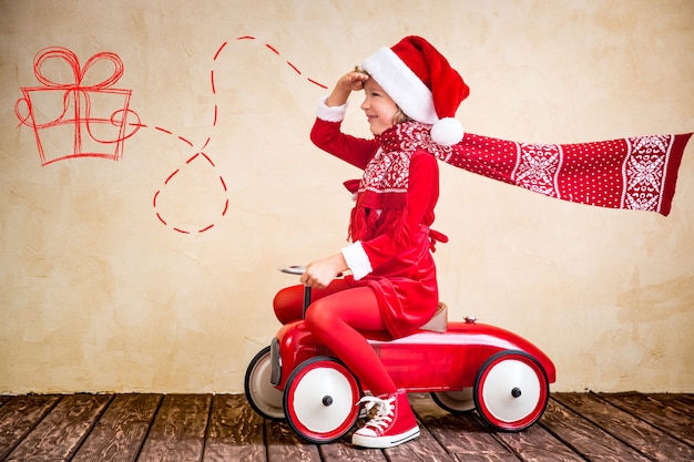 Paseo infantil en coche rojo de Navidad. Concepto de vacaciones de Navidad