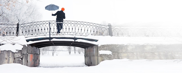 Paseo de invierno con un paraguas Hombre con un abrigo con un paraguas, caminar con el telón de fondo del paisaje invernal, vista de invierno