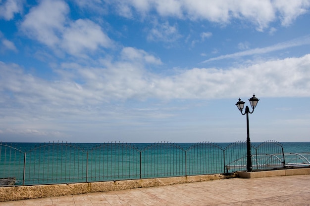 Paseo marítimo con farola y cielo azul con nubes