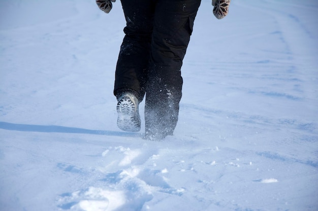 Un paseo por la nieve una chica con ropa de deportes de invierno y zapatos de trekking se va caminando