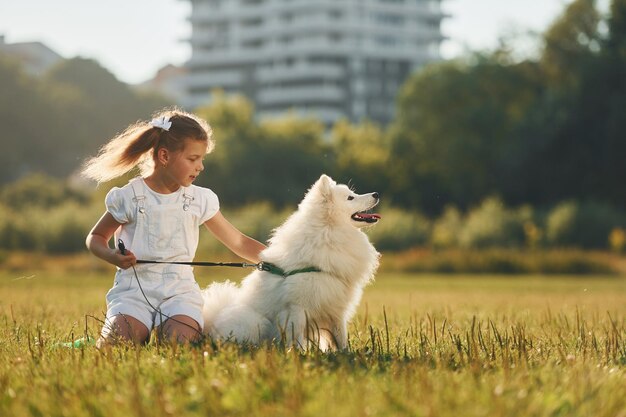 En el paseo Niña con su perro se divierte en el campo durante el día soleado