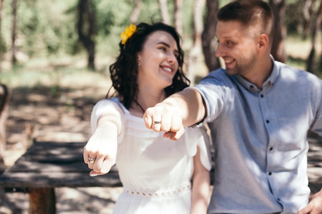 Foto paseo nupcial en el pinar. día soleado. novios en el bosque. hermosa novia y el novio en un paseo. vestido de novia blanco. ramo de peonías y hortensias.