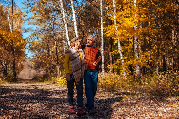 Paseo de otoño Senior pareja caminando en el parque de otoño. Feliz hombre y mujer hablando y relajándose al aire libre