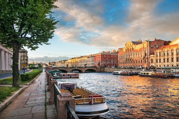 Paseos en barco por el río Fontanka en San Petersburgo en una tarde soleada de verano y el puente Anichkov en la distancia
