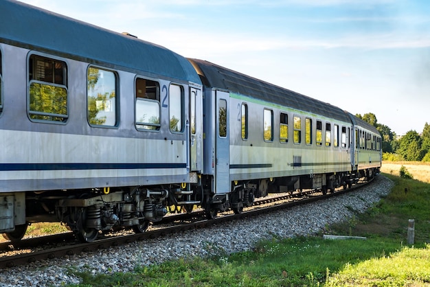 Paseos en tren de pasajeros entre campos en un día soleado