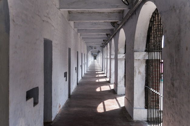 Pasillo en un ala de la cárcel celular de Port Blair, islas Andaman y Nicobar, India. Celdas de confinamiento solitario a lo largo de la pared blanca de una antigua prisión