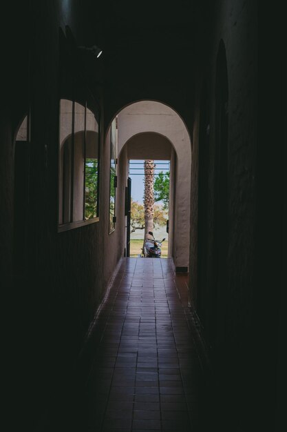 Pasillo común de una vivienda latina con piso de loseta y con una moto a la salida Foto vertical