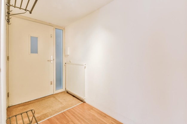 Pasillo de entrada que conduce al interior de un acogedor apartamento residencial con suelo blanco y de madera