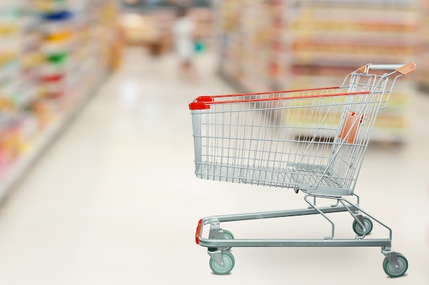 Pasillo del supermercado con carrito de compras vacío en el concepto de negocio minorista de la tienda de comestibles