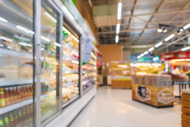 Pasillo de supermercado con congelador de refrigeradores comerciales que muestra alimentos congelados fondo borroso abstracto