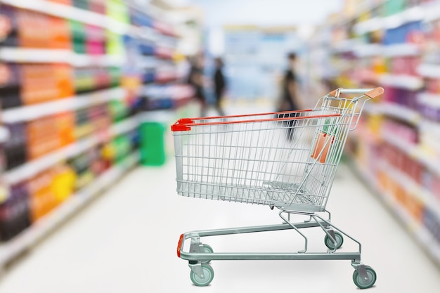 Pasillo de supermercado desenfoque de fondo desenfocado con carrito de compras rojo vacío