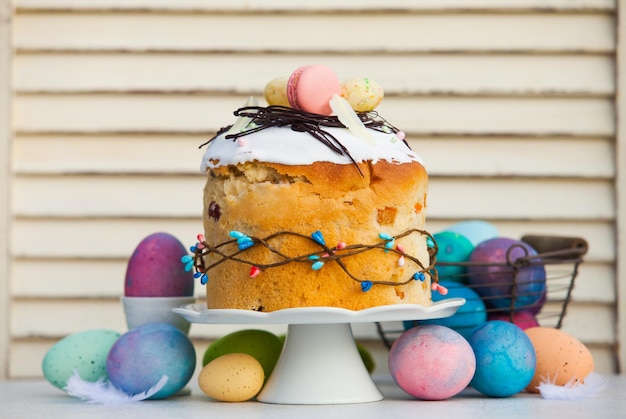 Paska de pão de Páscoa tradicional assado profissionalmente com decoração elegante no topo Ovos multicilor ao redor do suporte de bolo com pão de Páscoa nele Conceito de férias de primavera