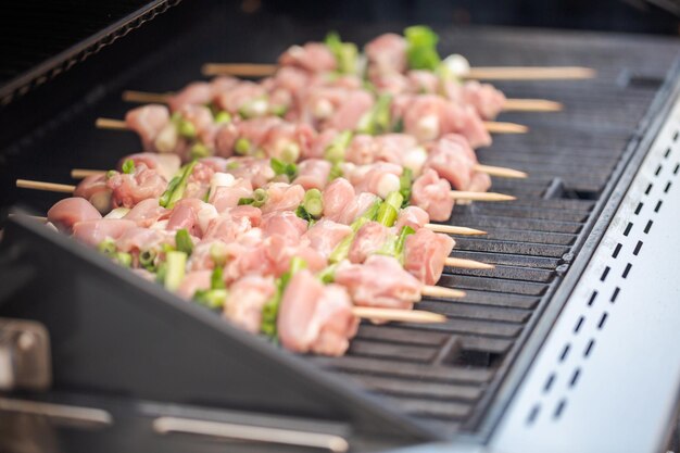 Paso a paso. Brochetas de yakitori de pollo crudo en una parrilla de gas al aire libre.