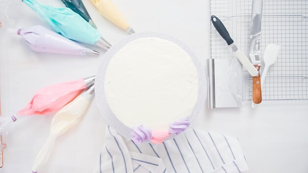 Paso a paso. Chef pastelero con glaseado de crema de mantequilla en pastel de unicornio para la fiesta de cumpleaños de una niña.