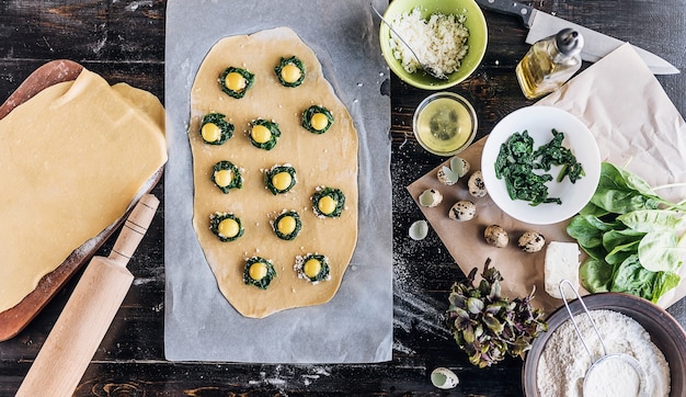 Paso a paso el chef prepara ravioles con queso ricotta, yemas de huevos de codorniz y espinacas con especias. El chef prepara el relleno de la masa.