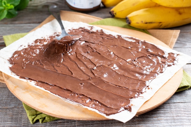 Paso a paso cocinando delicioso rollo con rodajas de plátano en mesa de madera. Rollo de plátano con postre de chocolate