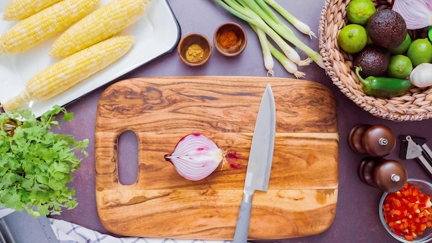 Paso a paso. Cortar cebolla morada en una tabla para cortar madera.