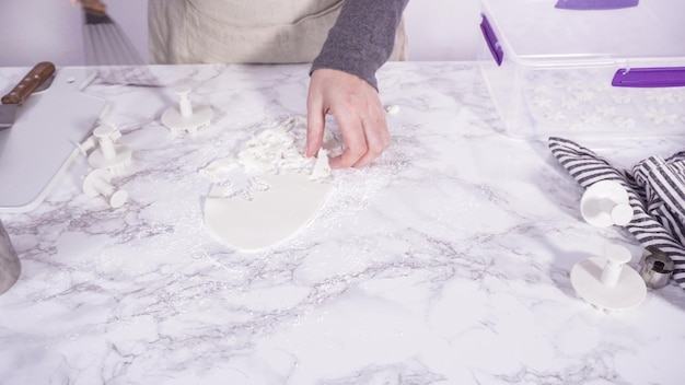 Paso a paso. Cortar copos de nieve con cortadores de galletas de fondant blanco en un mostrador de mármol.