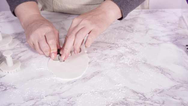 Paso a paso. Cortar copos de nieve con cortadores de galletas de fondant blanco en un mostrador de mármol.