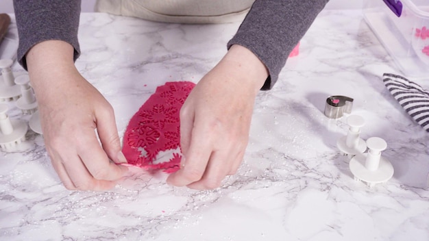 Paso a paso. Cortar copos de nieve con cortadores de galletas de fondant rosa en un mostrador de mármol.