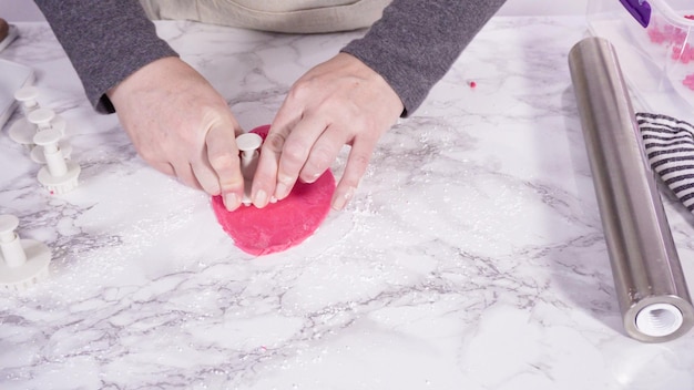 Paso a paso. Cortar copos de nieve con cortadores de galletas de fondant rosa en un mostrador de mármol.