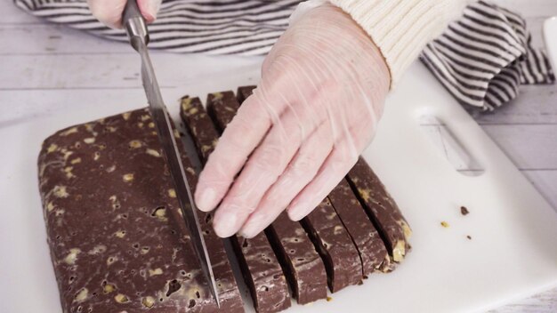 Paso a paso. Cortar dulce de macadamia casero en una tabla de cortar blanca.