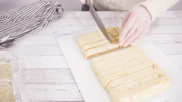 Paso a paso. Cortar fudge de bastón de caramelo casero en una tabla de cortar blanca.