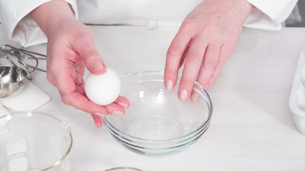 Paso a paso. Craquear huevos orgánicos blancos en un tazón de vidrio pequeño.