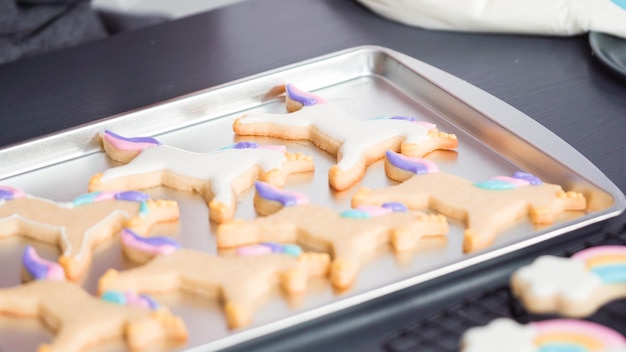Paso a paso. Decoración de galletas de azúcar de unicornio con glaseado real en una bandeja para hornear.