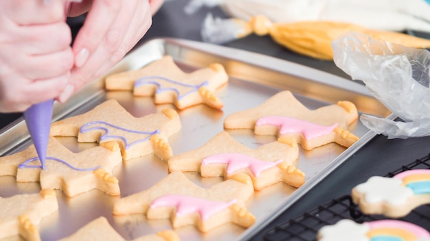 Paso a paso. Decoración de galletas de azúcar de unicornio con glaseado real en una bandeja para hornear.