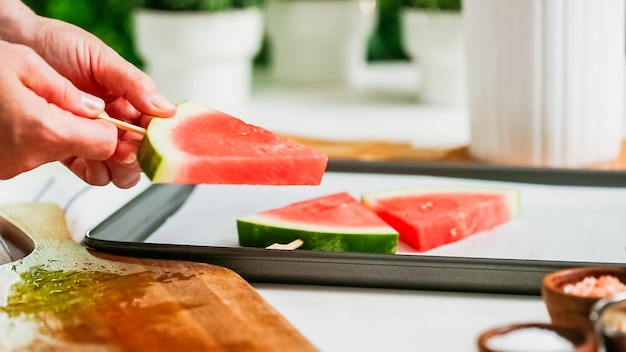 Paso a paso. Deslizar el palito de paleta de madera en la cuña de sandía para hacer paletas heladas de sandía.